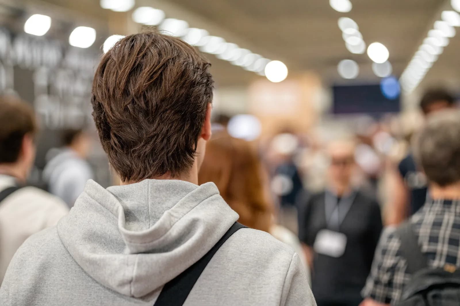 Asistentes circulando por el piso de expo de un congreso, vistos desde atrás.